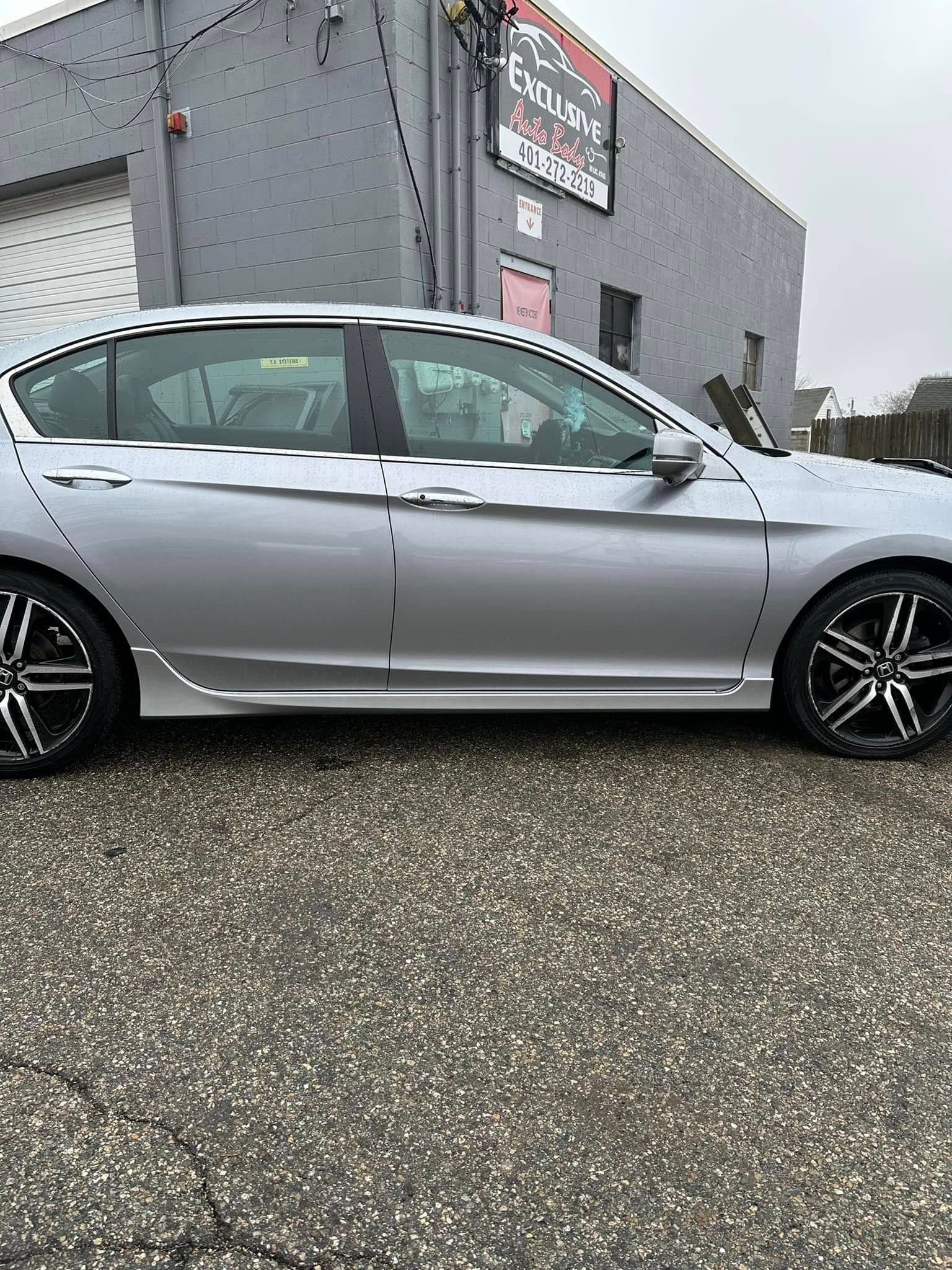 A silver car is parked in front of a building.