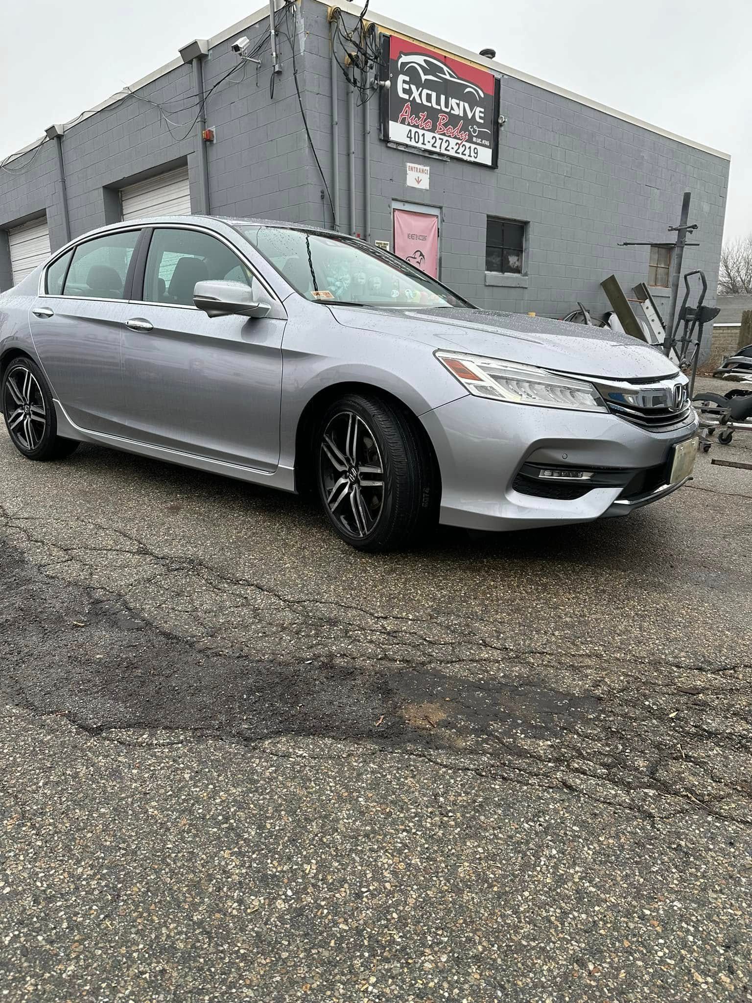 A silver honda accord is parked in front of a building.