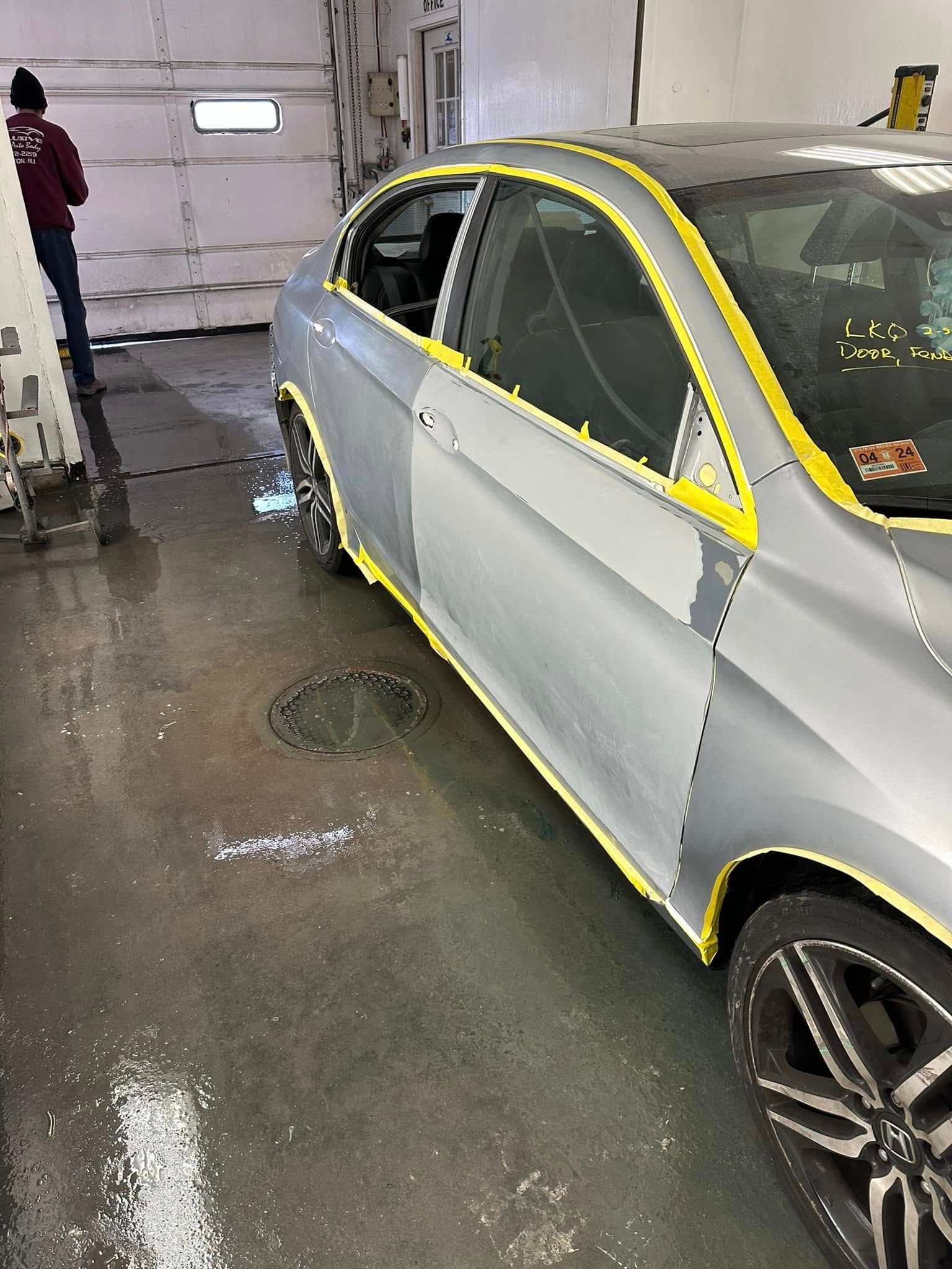 A car is being painted in a garage with yellow tape.