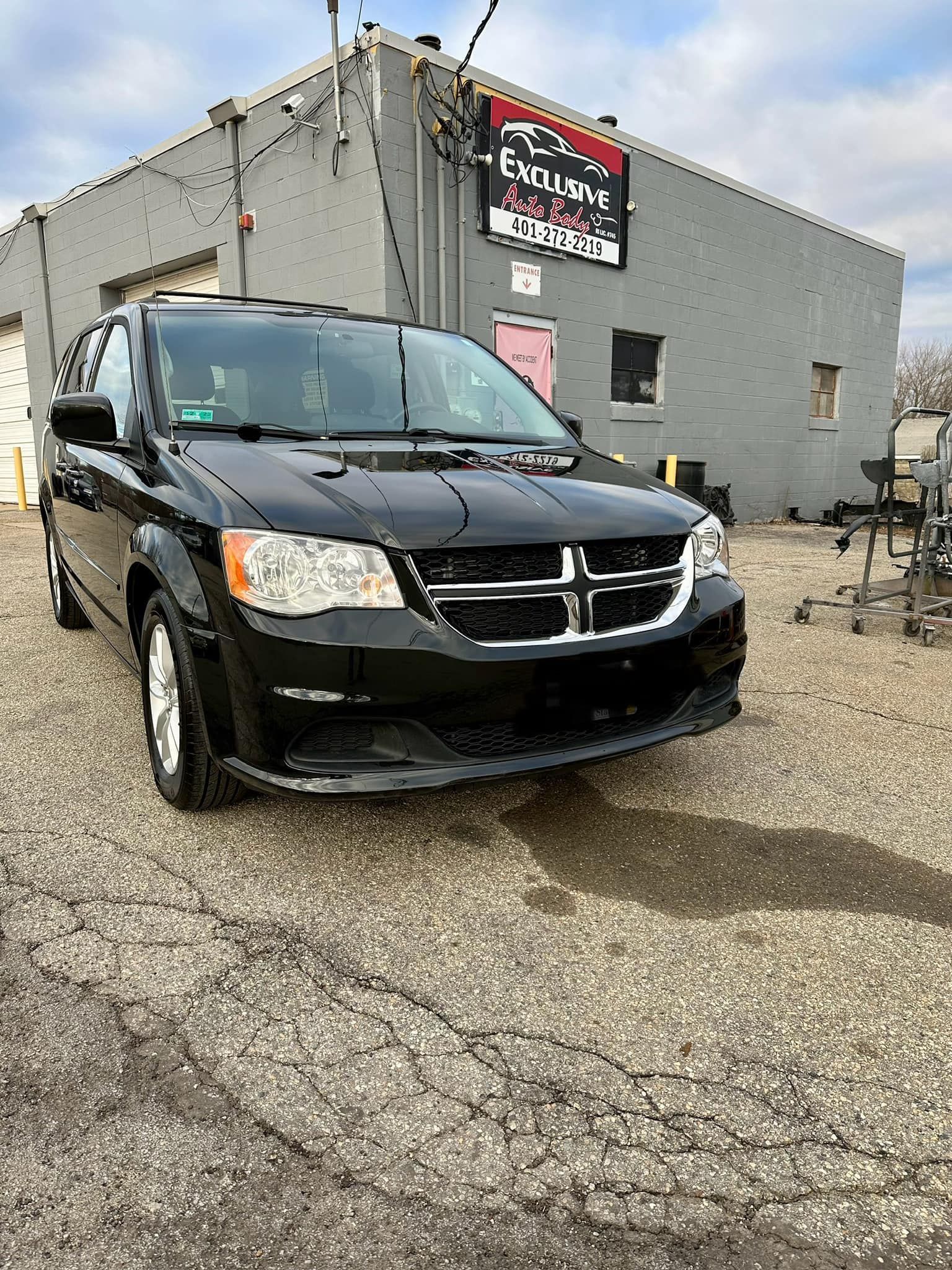 A black dodge caravan is parked in front of a building.