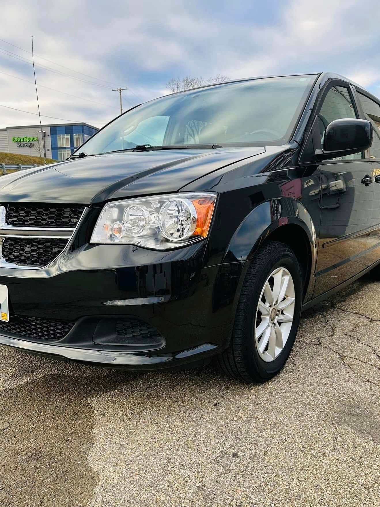 A black minivan is parked on the side of the road.