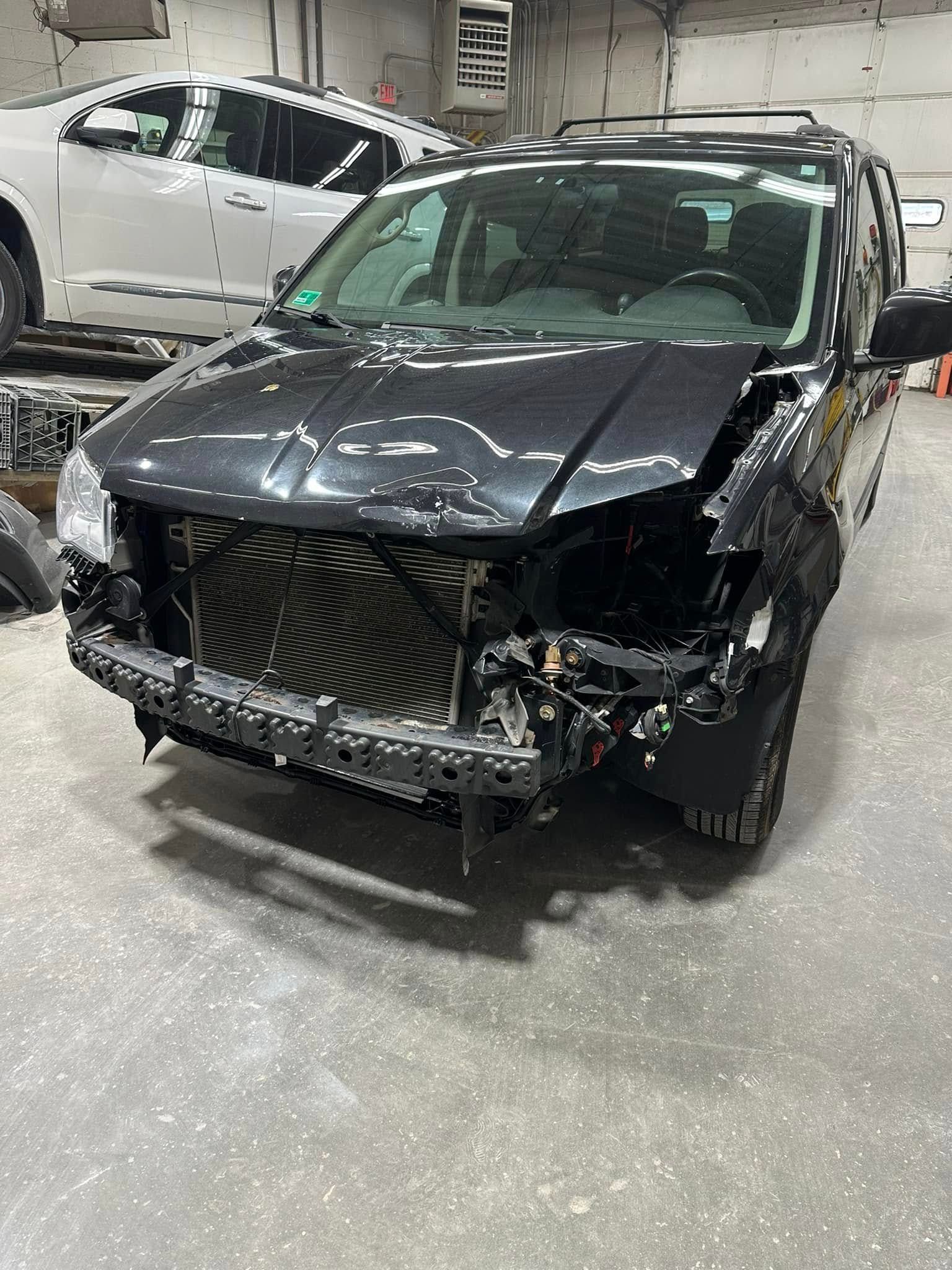 A black jeep is sitting in a garage with its front end missing.