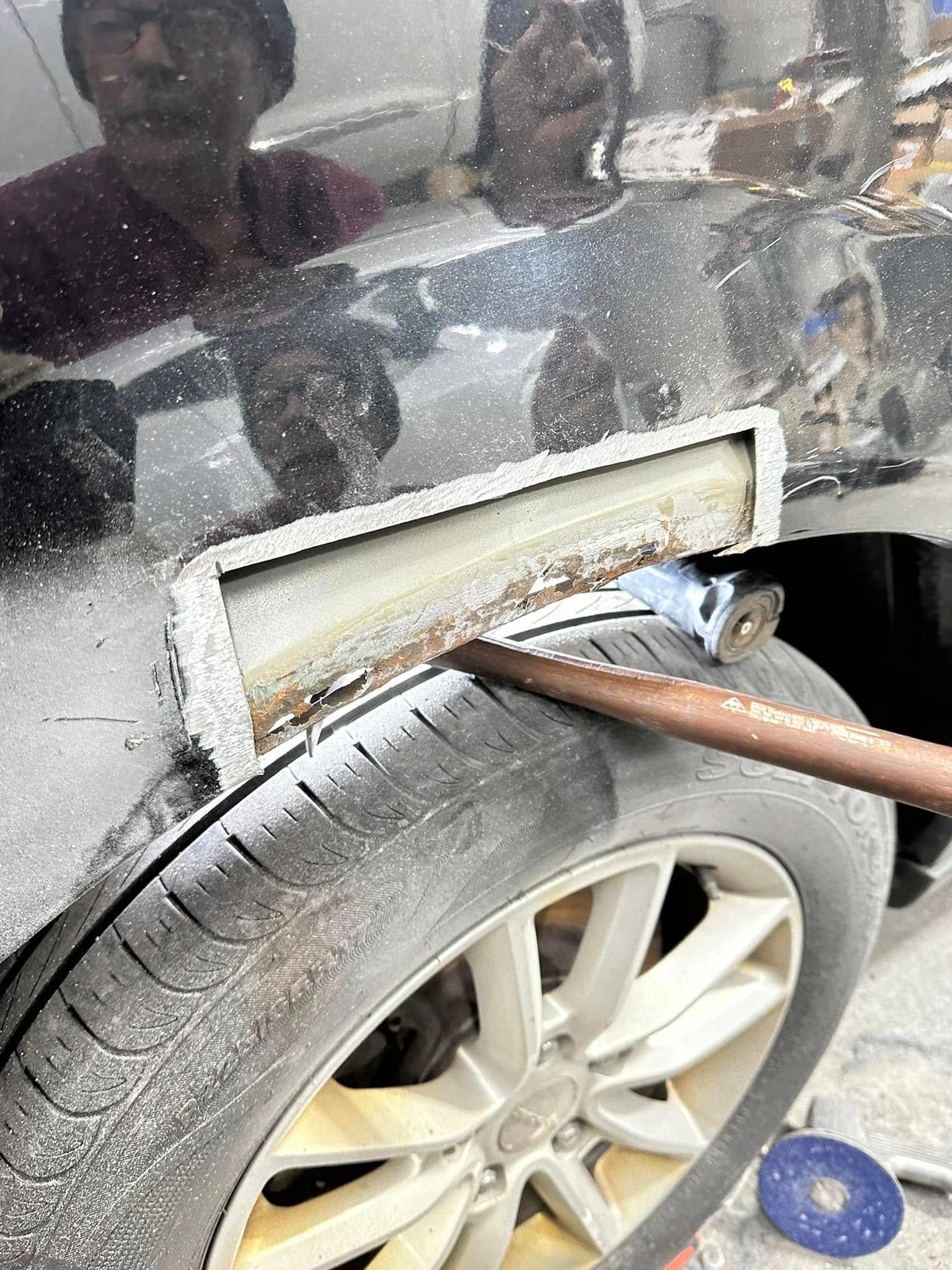 A man is welding a fender on a car.