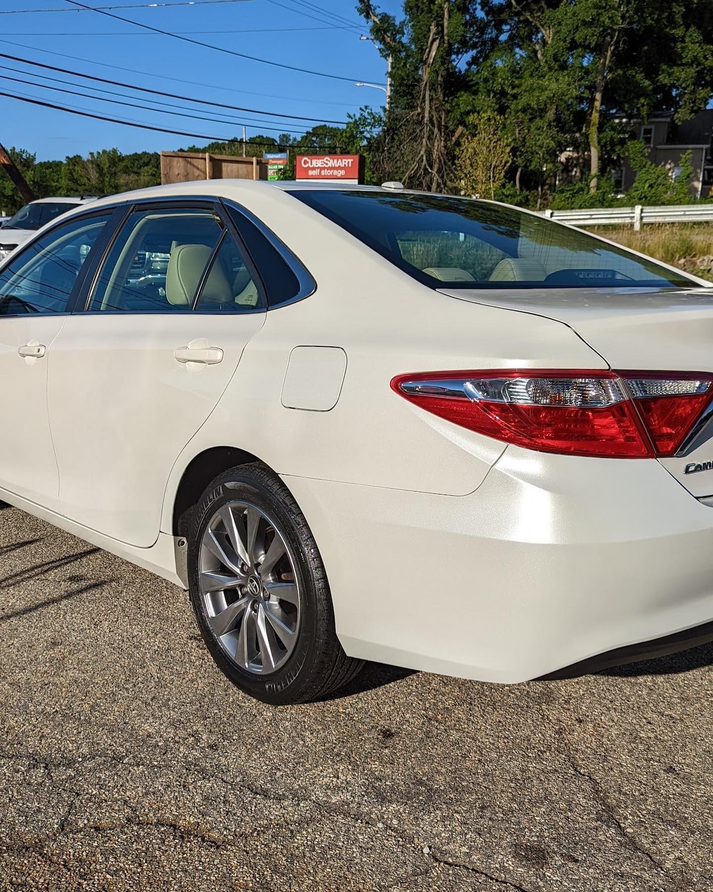 A white toyota camry is parked in a gravel lot.