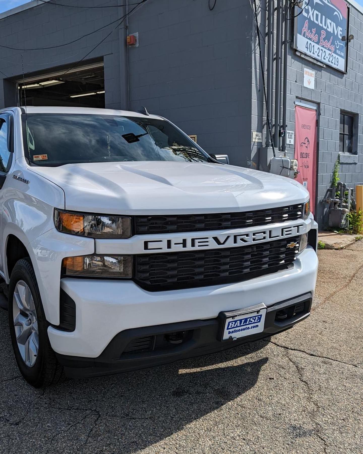 A white chevrolet truck is parked in front of a building.