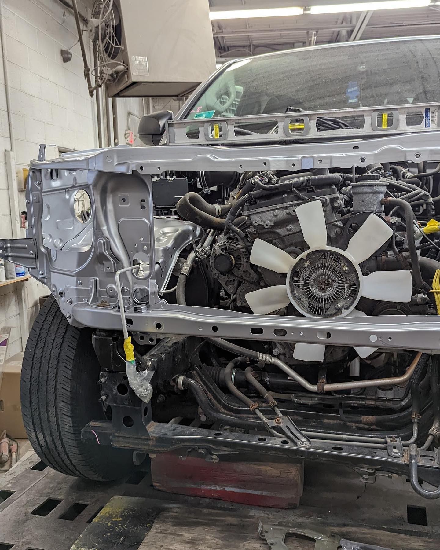 The front end of a truck is being dismantled in a garage.