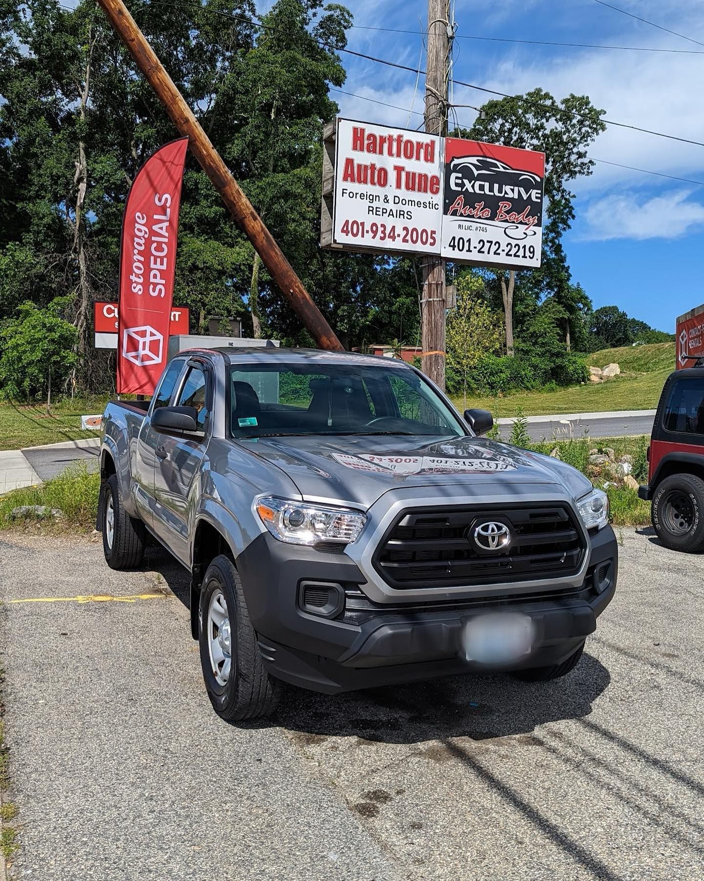 A silver toyota tacoma is parked in front of a car dealership.
