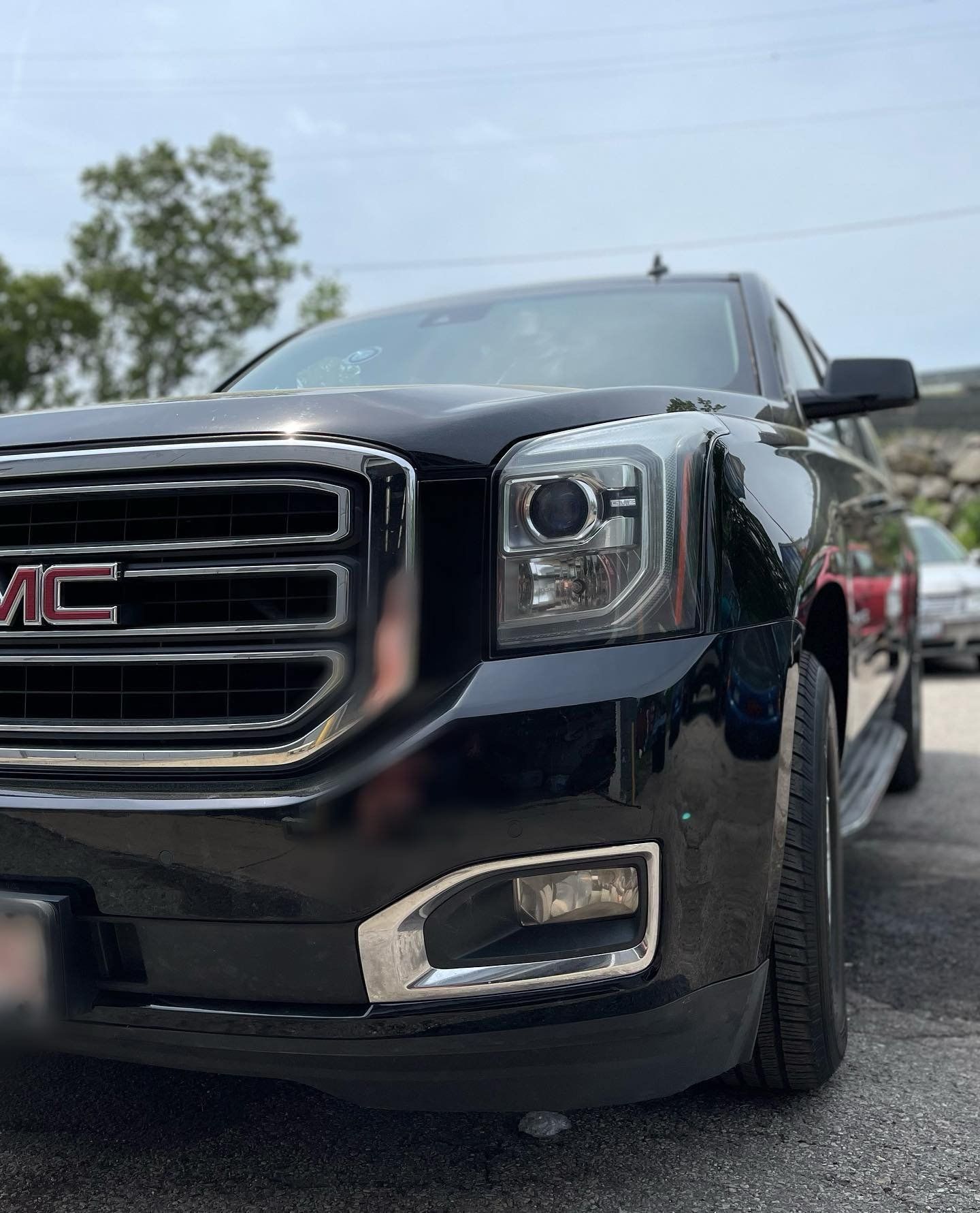 The front end of a black gmc yukon is parked in a parking lot.