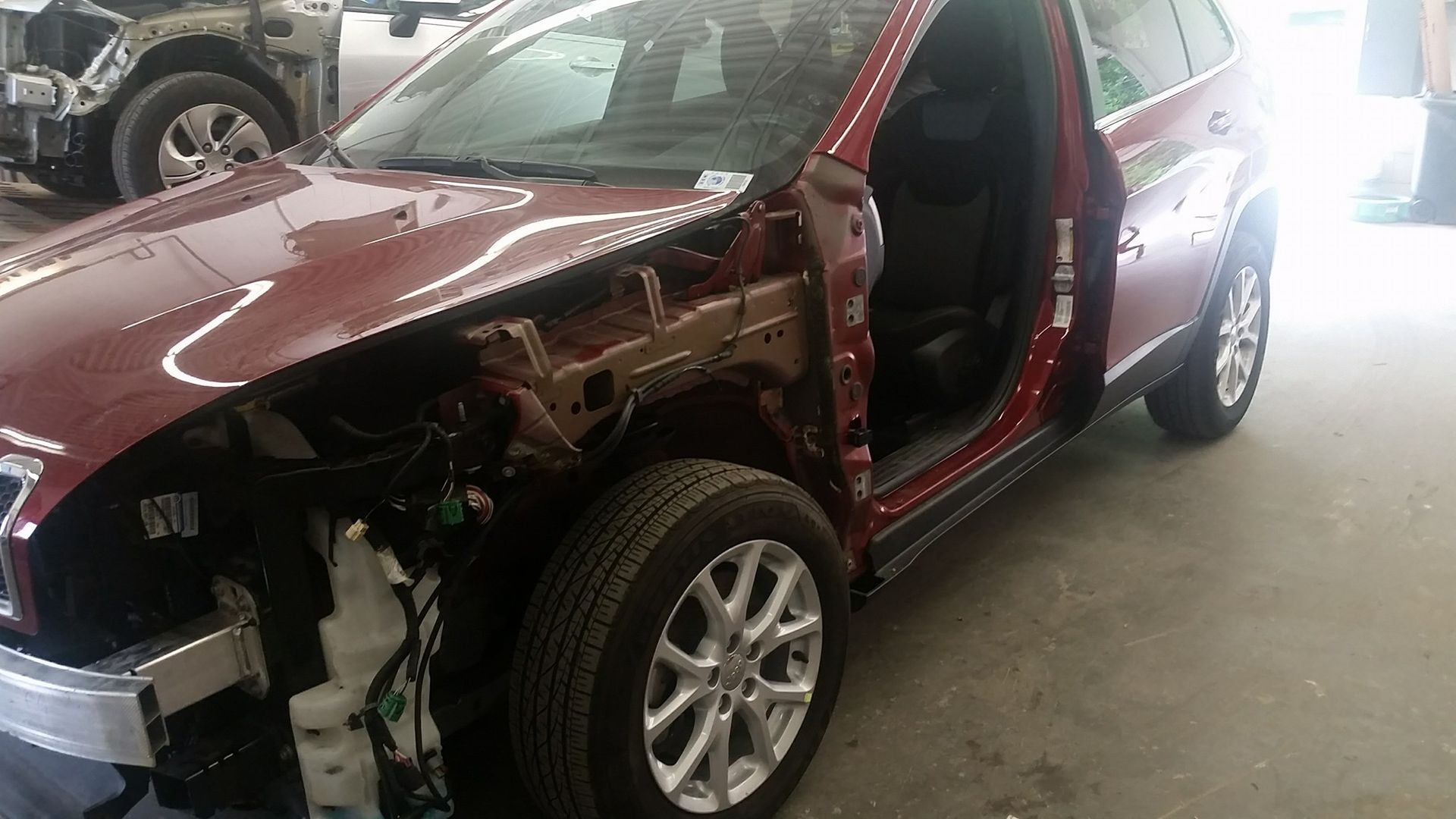 A red car is sitting in a garage with the door open.