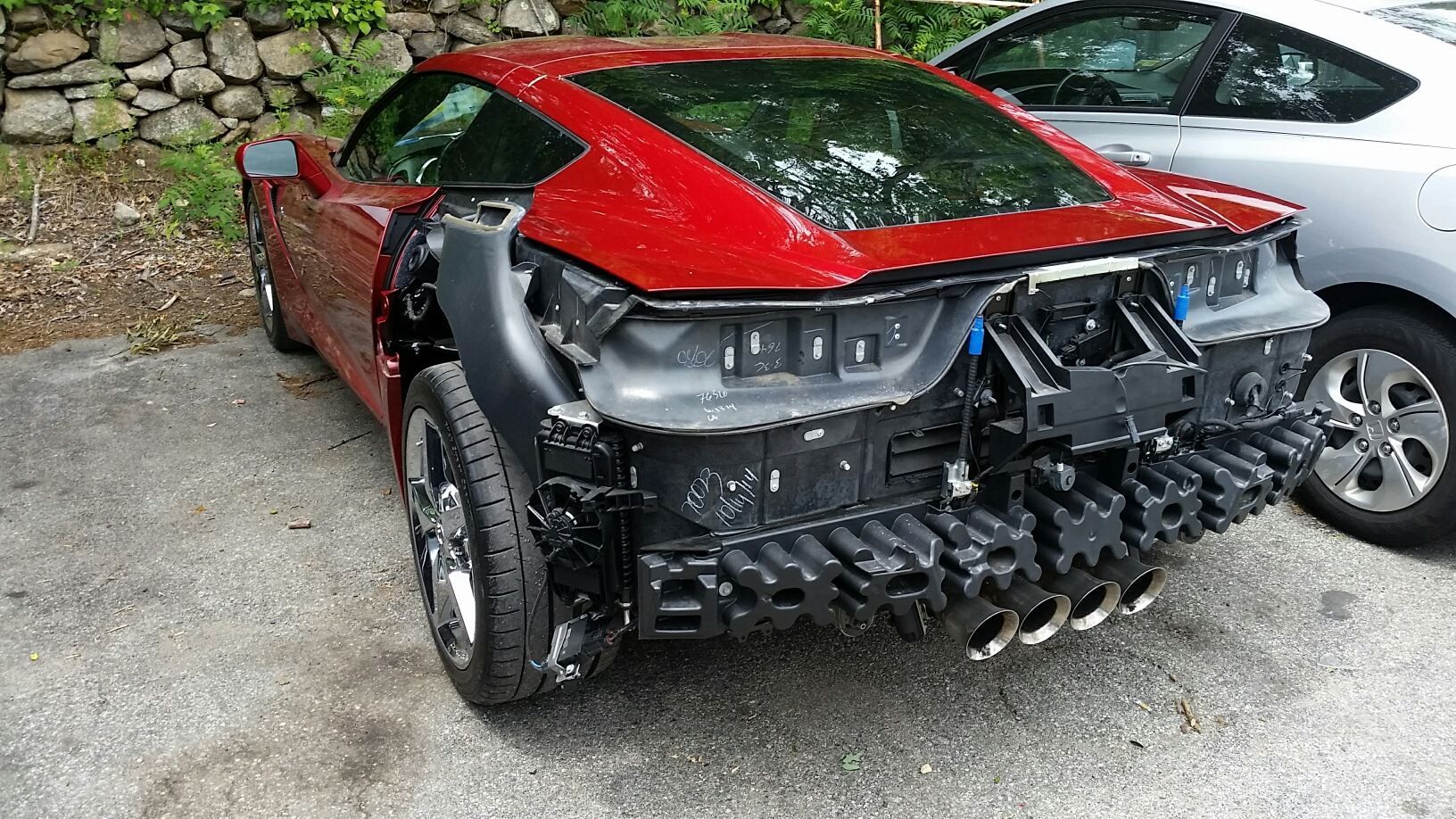 A damaged red sports car is parked next to another car