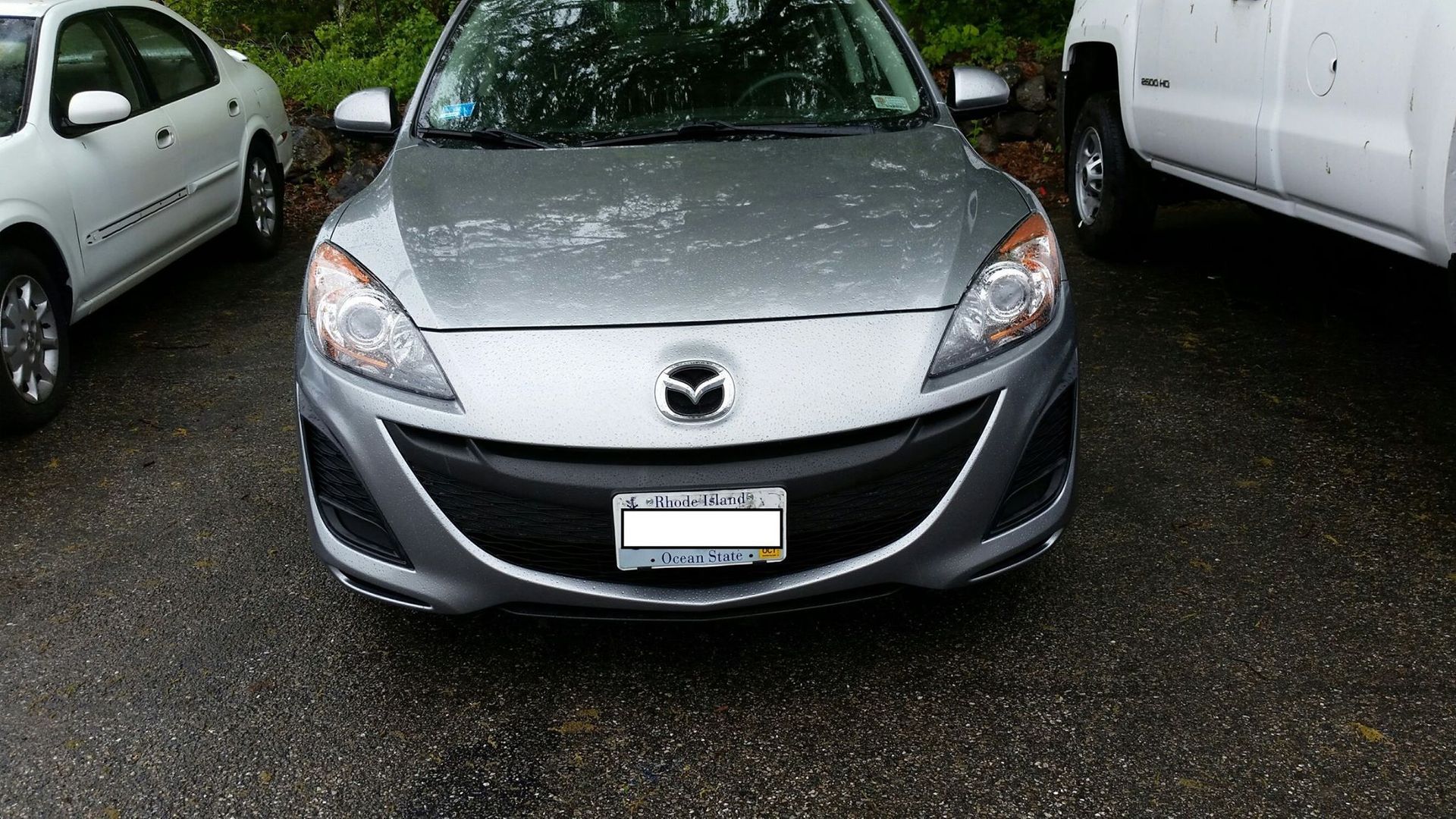 A gray mazda car is parked in a parking lot