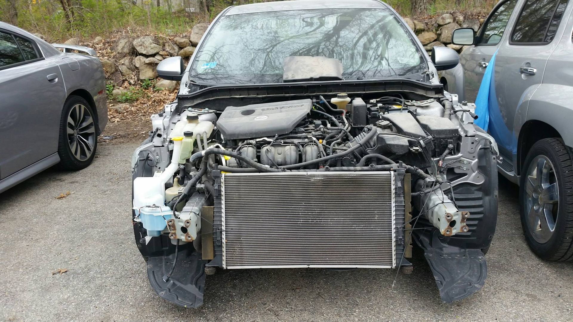 A car with the hood up is parked in a parking lot.