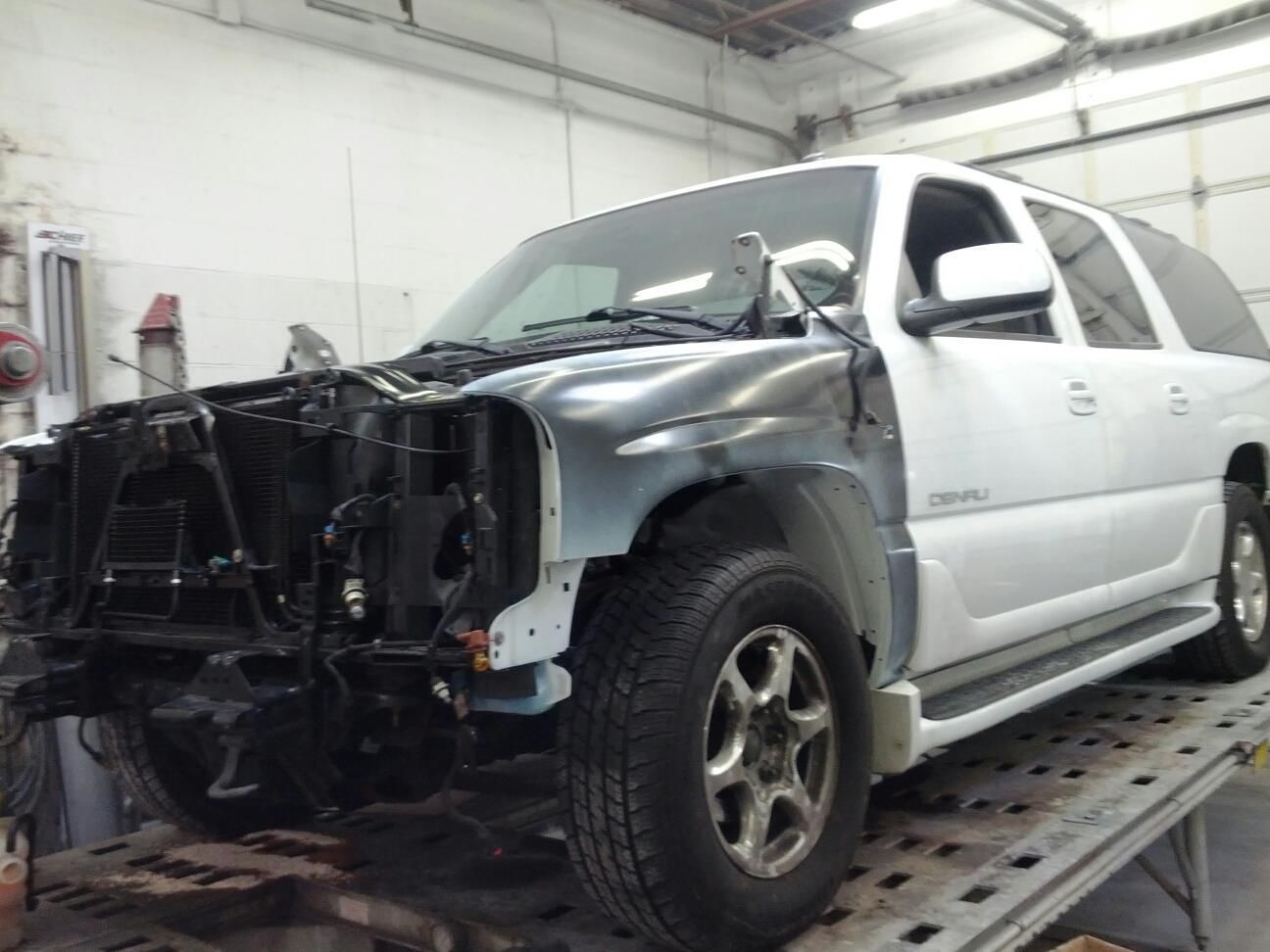 A white suv is sitting on a tow truck in a garage