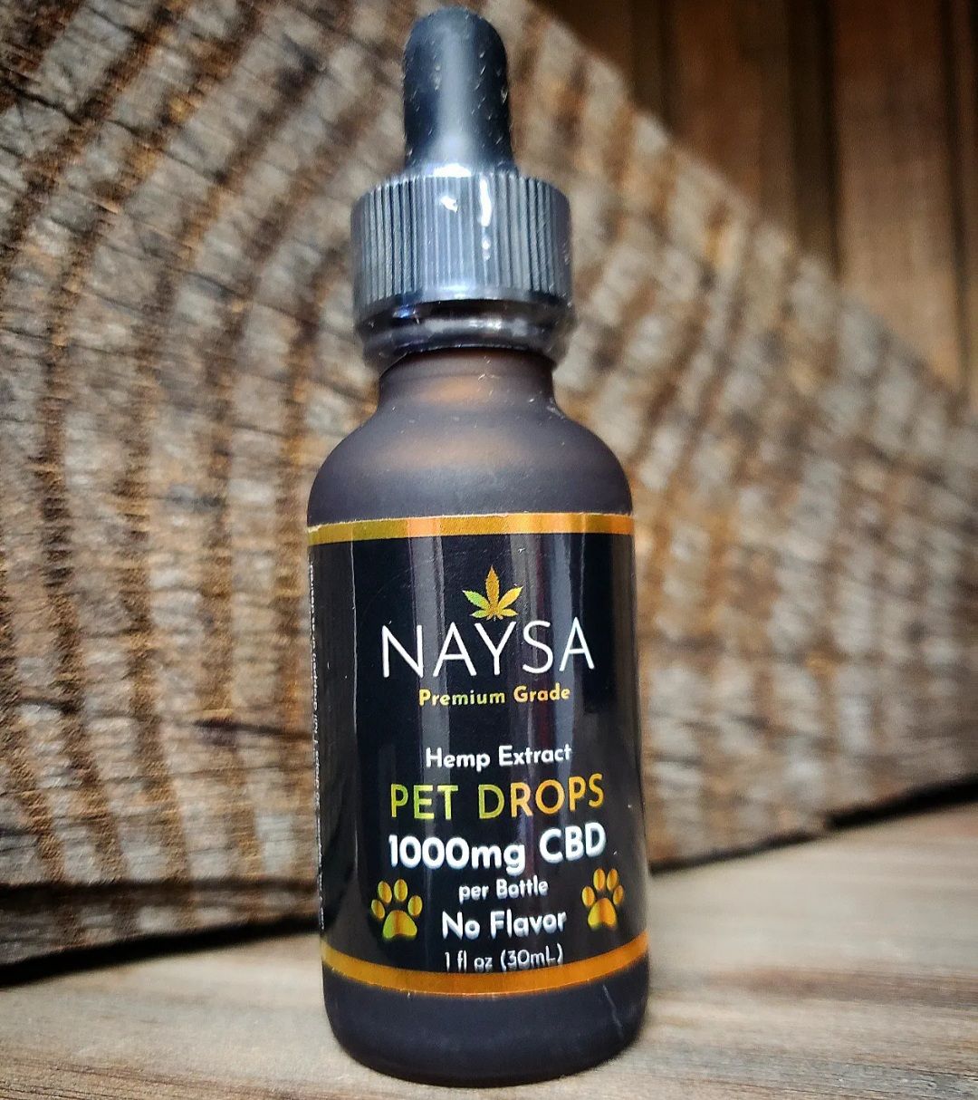 A bottle of Naysa Pet Drops CBD oil for pets, 1000mg CBD, with a wooden background.