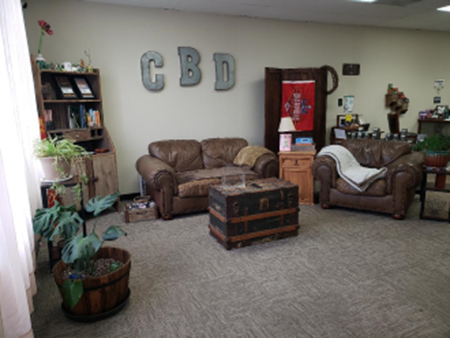 Cozy waiting area with brown leather furniture and “CBD” letters on the wall.