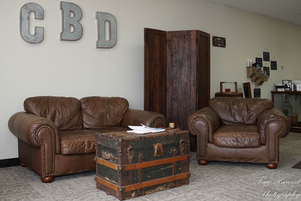 Leather seating area with a trunk table, a room divider, and CBD sign.