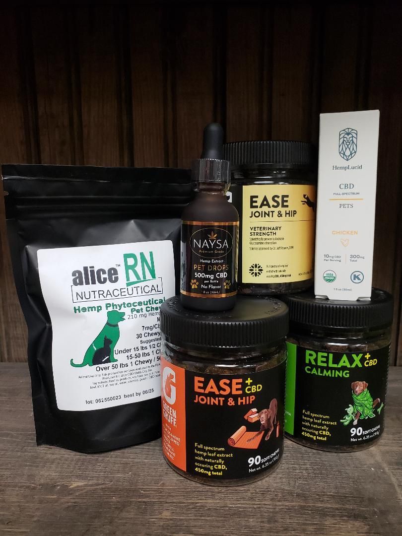 Various CBD products for pets, including chews, oil, and a treat bag, on a wooden surface.