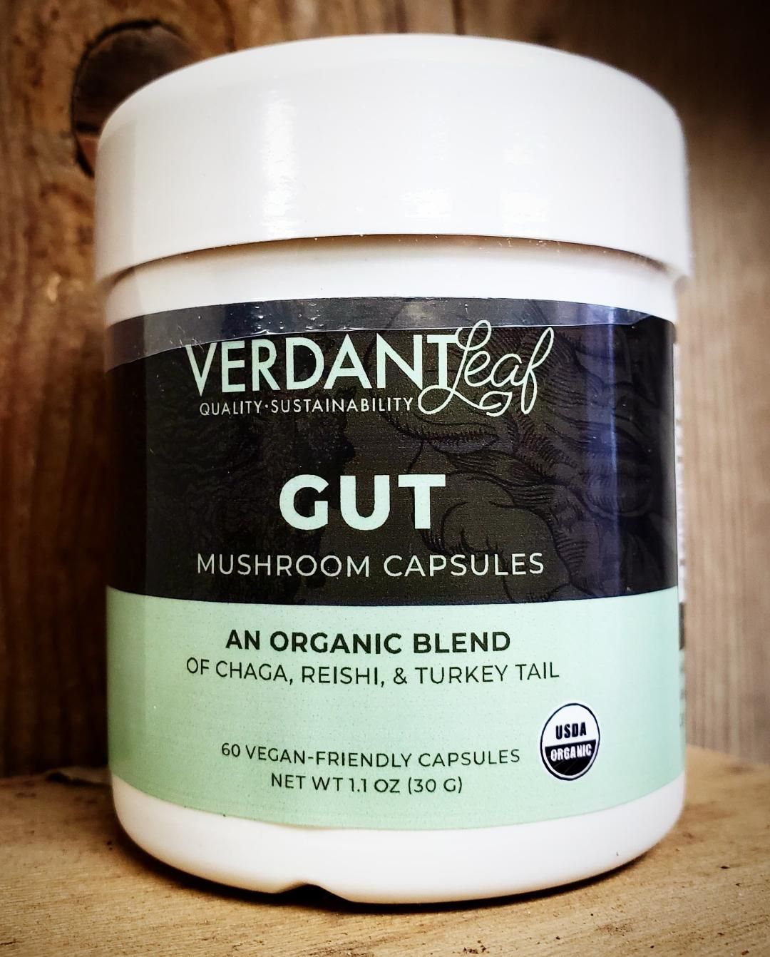Verdant Leaf Gut mushroom capsules jar with white lid and mint-green label on a wooden surface