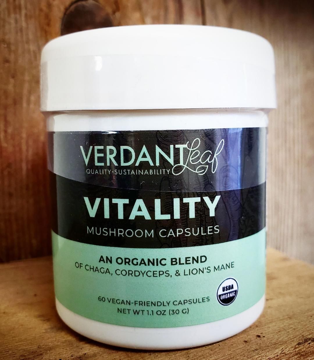 Verdant Leaf Vitality mushroom capsules bottle with white lid and green label on a wooden surface