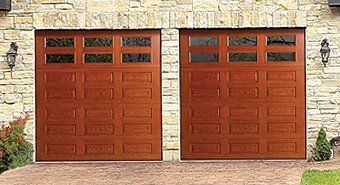 A pair of wooden garage doors in front of a stone building.