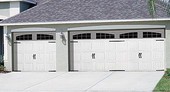 A house with two white garage doors and a gray roof.