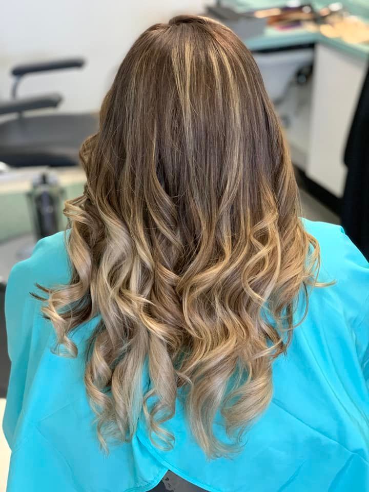 Woman with brown hair, highlighted with blonde, styled with waves and ombre effect.