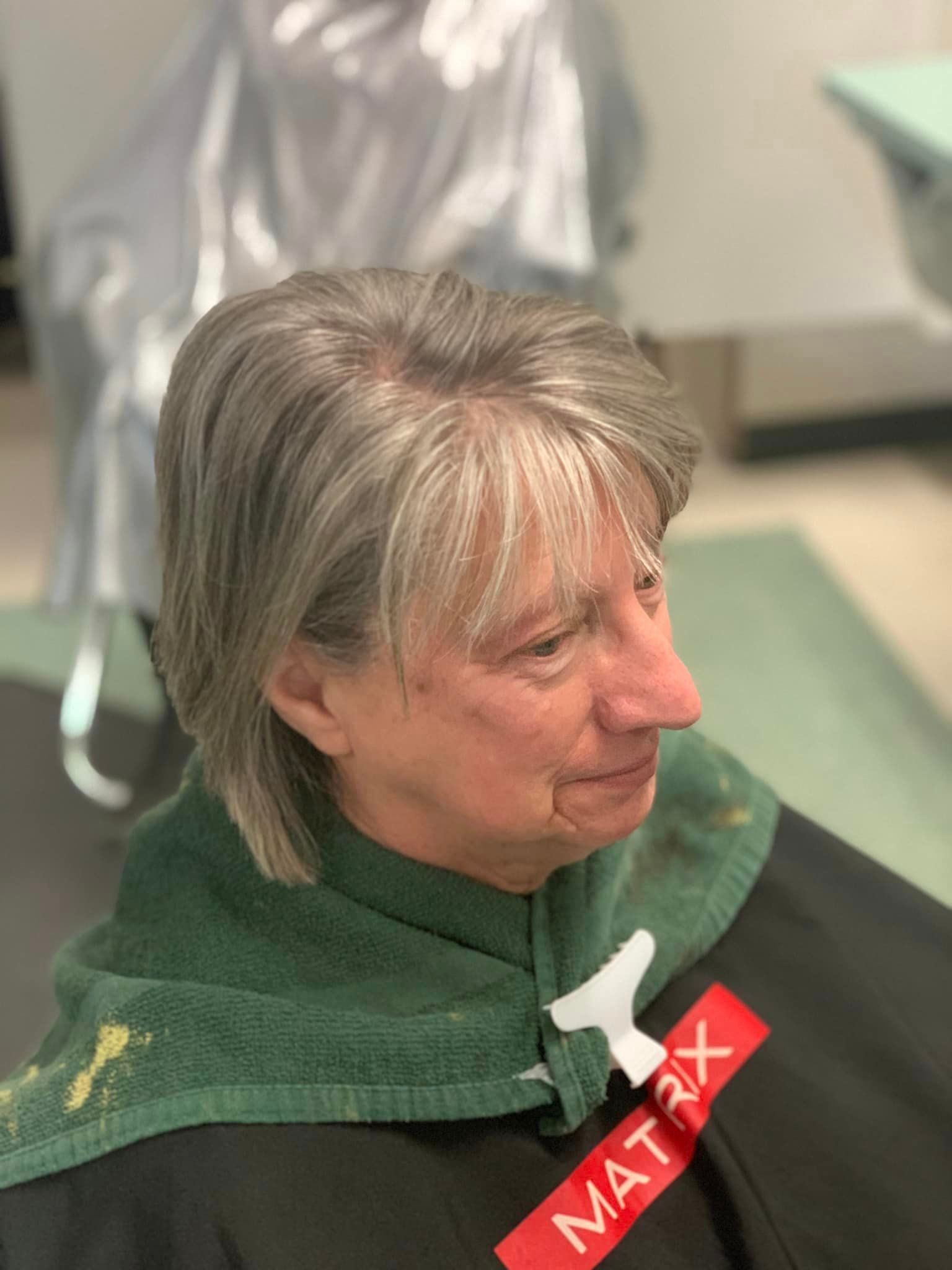 Woman with graying hair at a salon wearing a cape with 