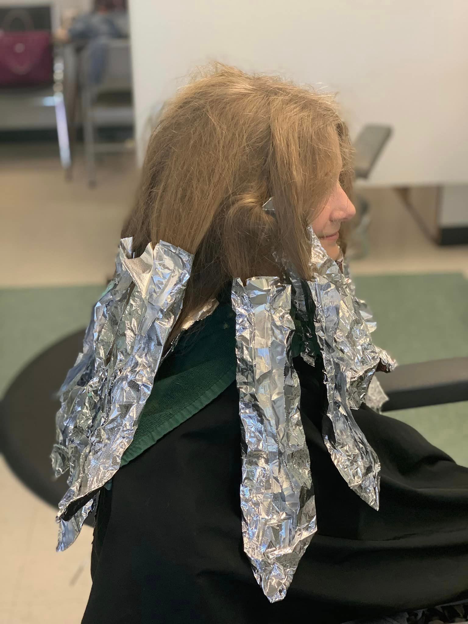 Person with hair wrapped in foil at a salon; getting highlights.