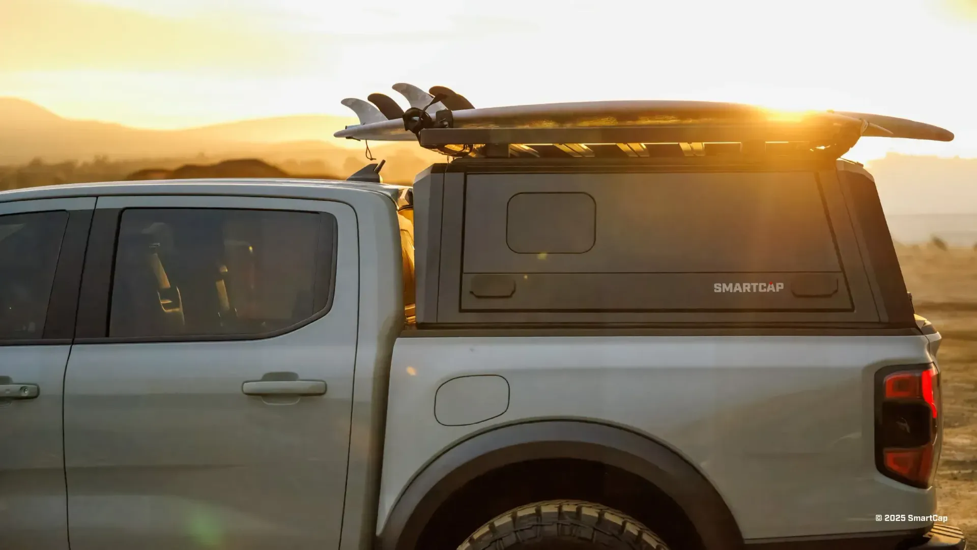 Truck bed with surfboards on the roof, silhouetted against a setting sun.