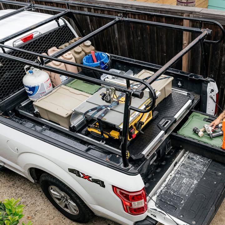 White truck bed with black rack, tools, and a pull-out bed storage unit.