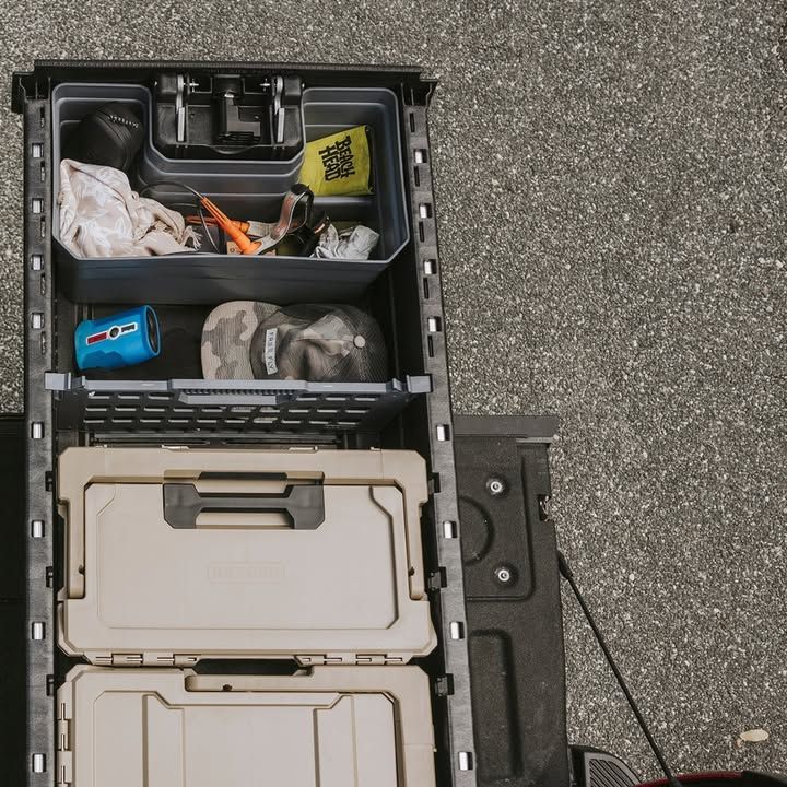Truck bed storage system with various compartments and boxes, gray asphalt background.