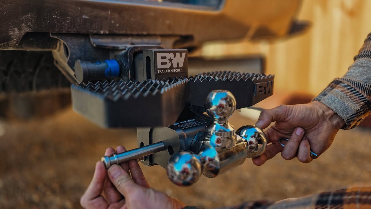 Person attaching a chrome trailer ball mount to a truck's hitch.