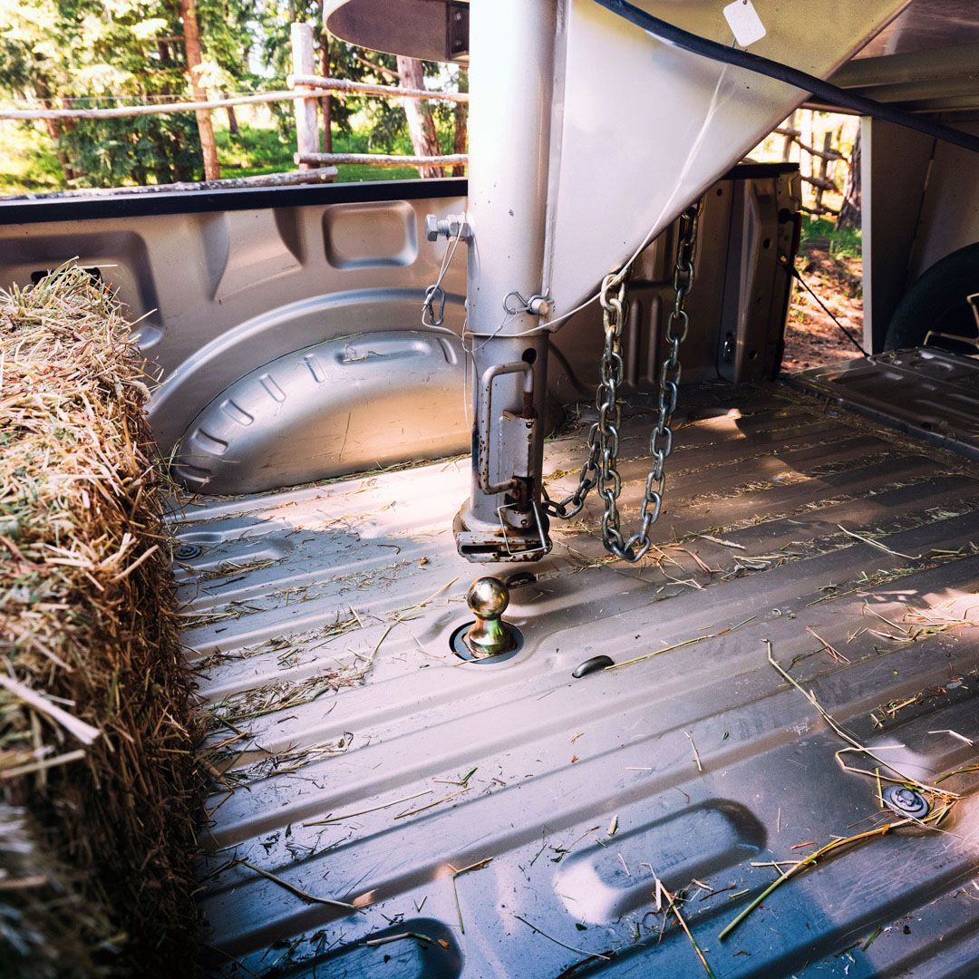 Truck bed with a gooseneck hitch, straw, and a trailer connection.