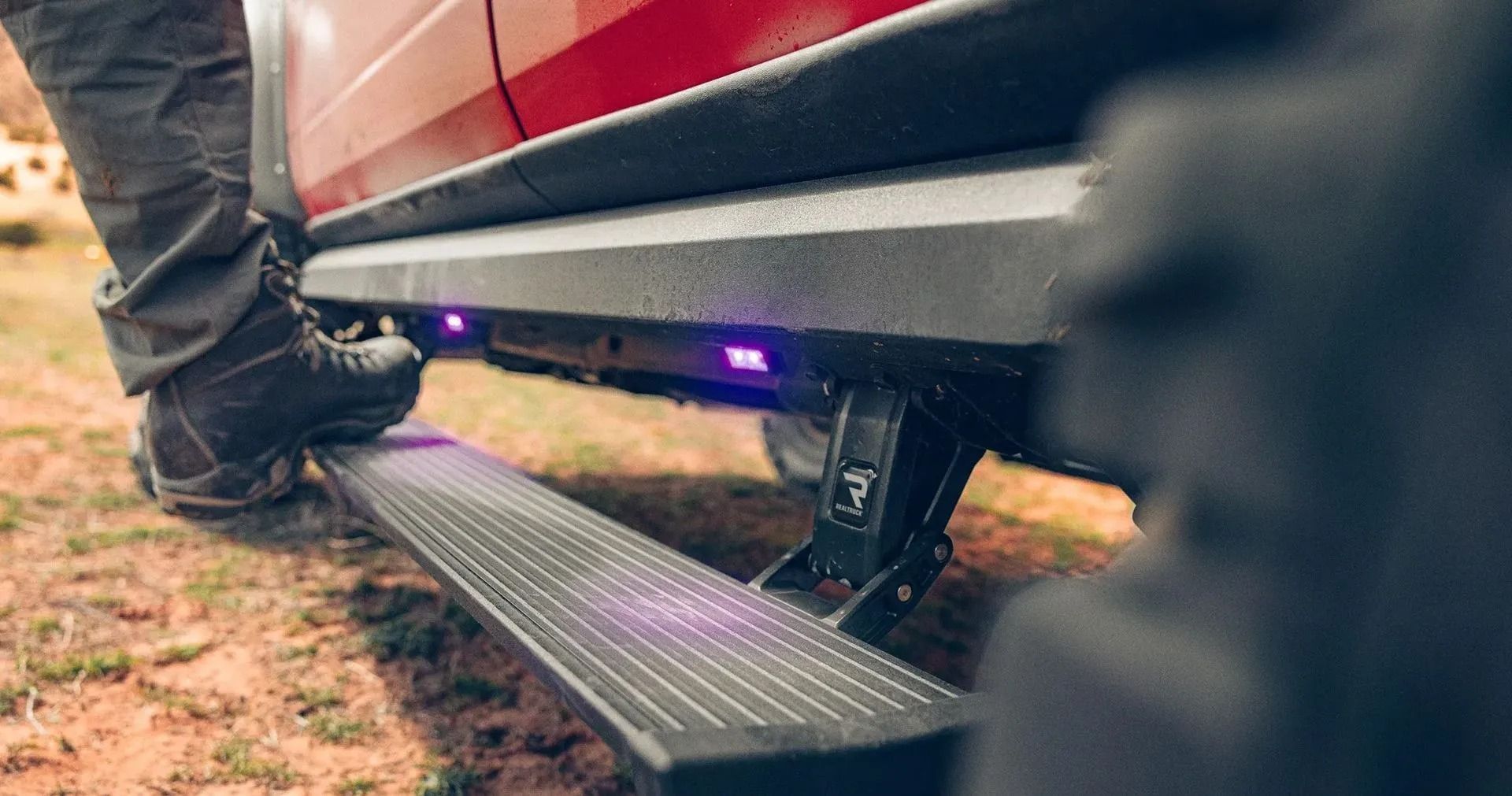 Person stepping onto a truck's running board with purple underglow lights illuminating the side.