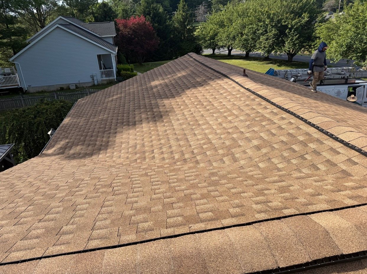 Tan shingle roof with a satellite dish, viewed from above in a sunny residential neighborhood