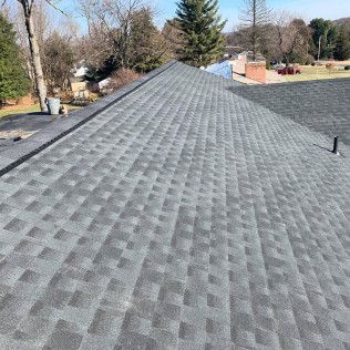 Gray shingled roof with ridge line, viewed from above on a sunny day