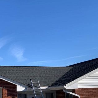 Ladder leaning against a house roof under a clear blue sky
