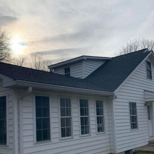 White house exterior with dark roof at dusk under a cloudy sky