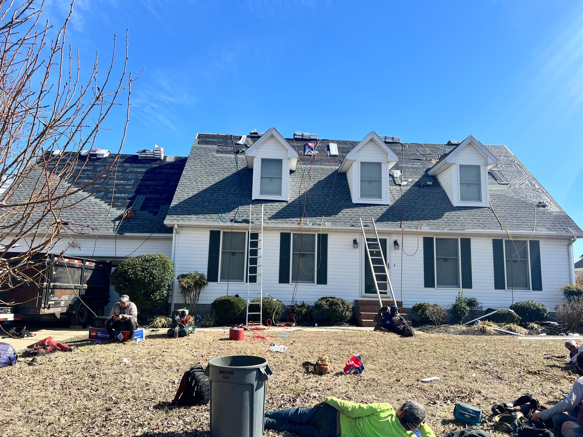 Two-story white house with blue roof and front yard decorated for the holidays