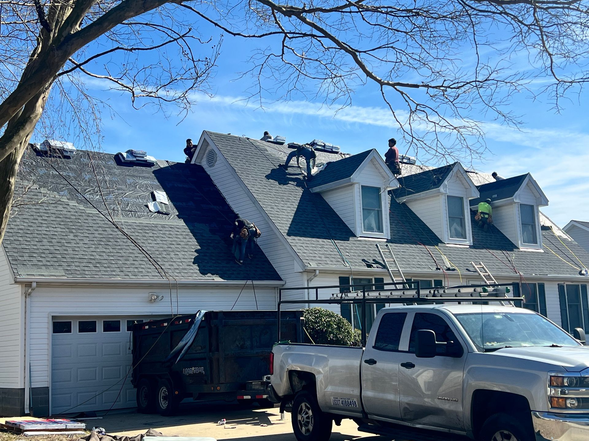 Pickup truck parked by a house with roof damage and a charred section near the garage
