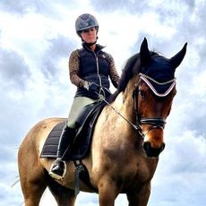 A woman is riding on the back of a brown horse.