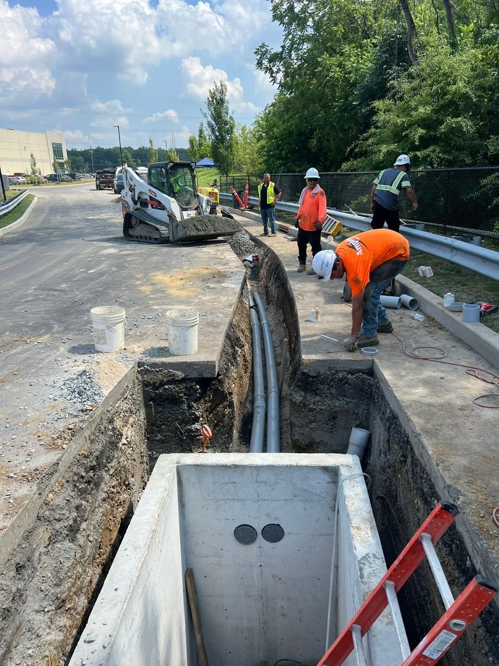 Roadwork site with workers in orange vests repairing underground utility trench beside a street