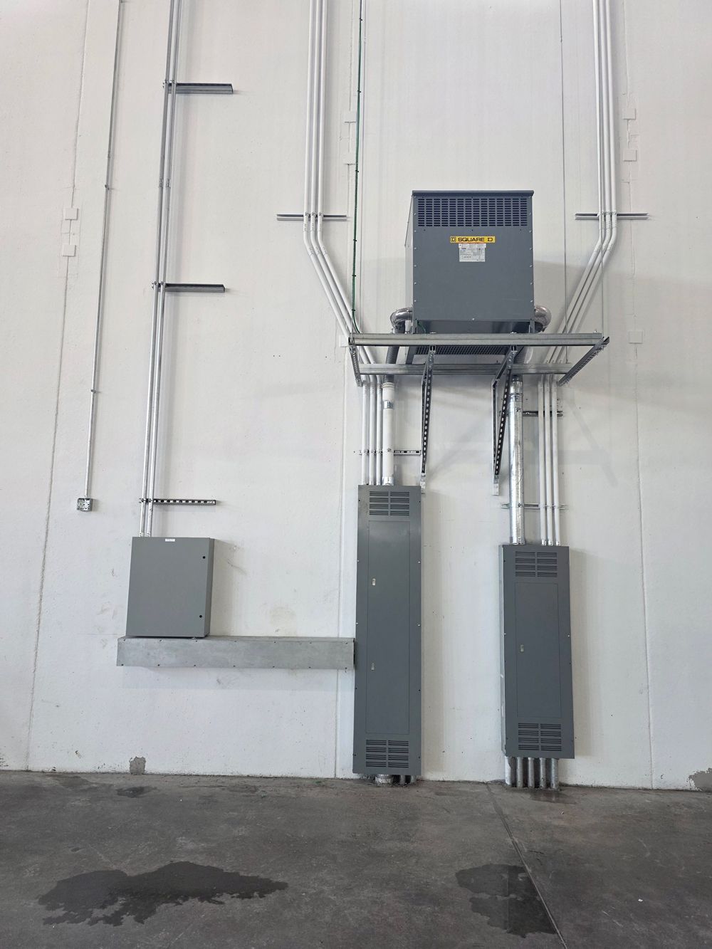 Industrial electrical panels and conduit mounted on a white wall in a utility room