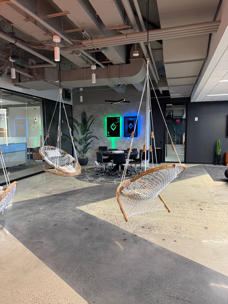 Damaged indoor lobby with exposed ceiling, debris, hanging wires, and a cracked floor near display screens