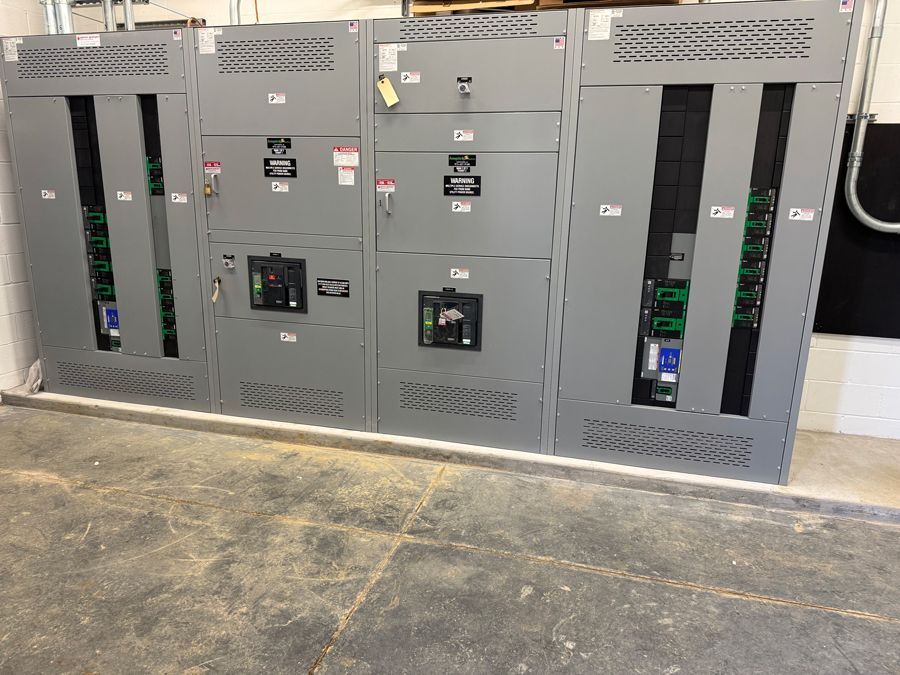 Row of gray electrical control cabinets with vents and inspection windows in an industrial room