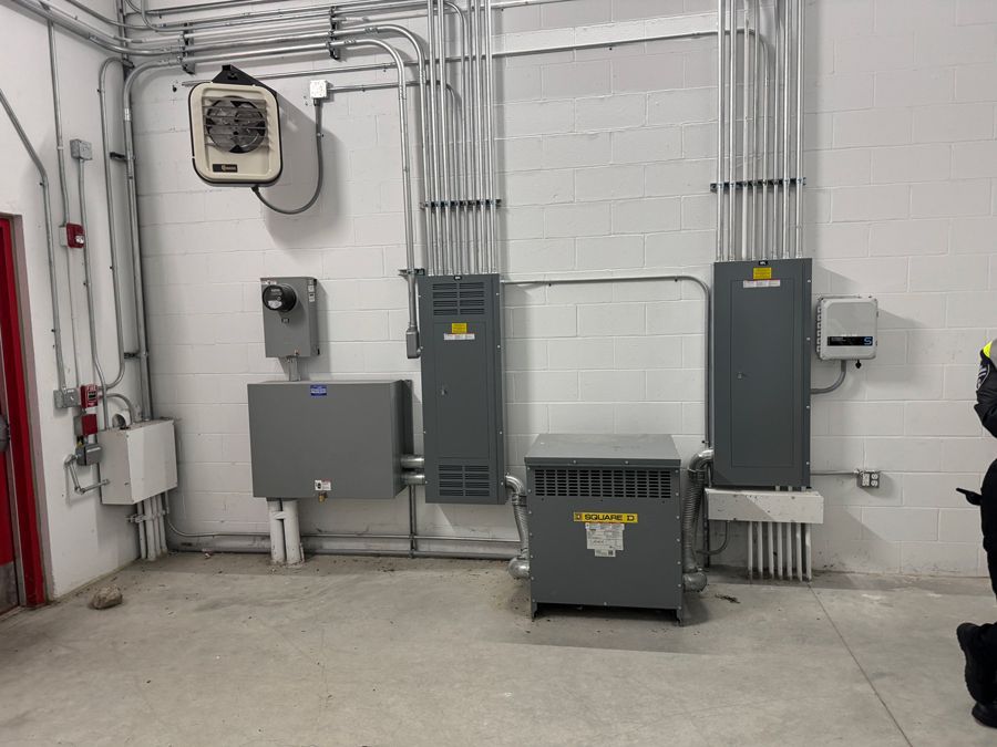 Electrical utility room with gray panels, conduits, and white cinderblock walls
