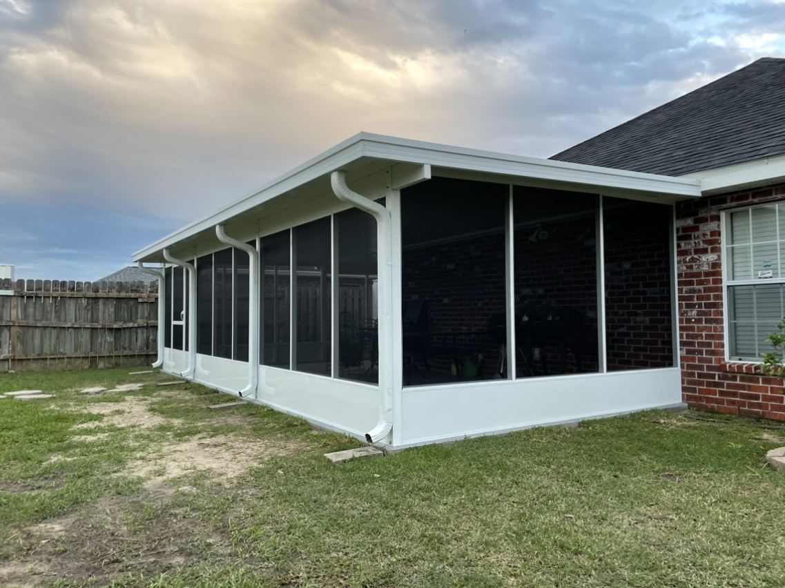 A screened in porch in the backyard of a house.