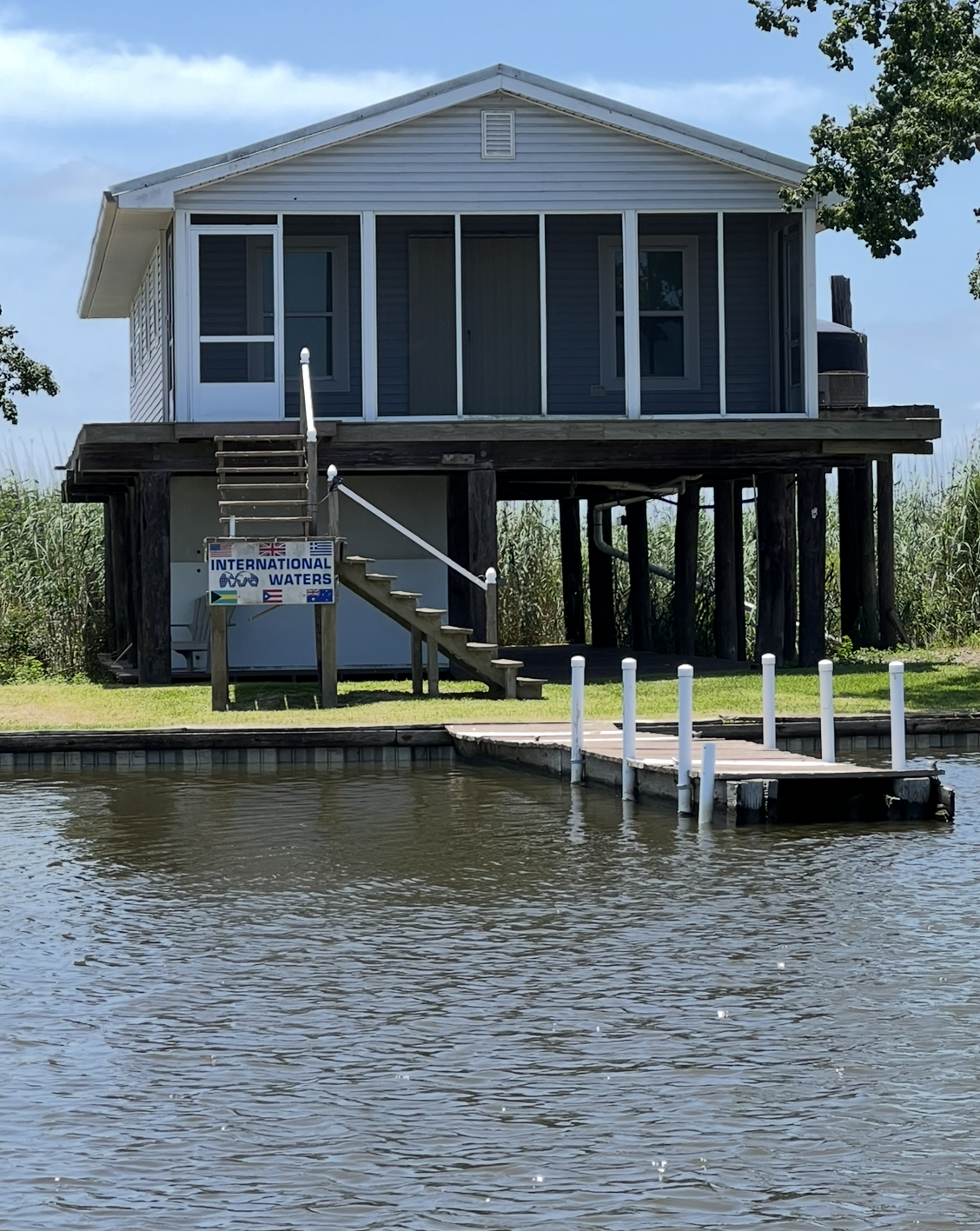 A house sitting on top of a body of water next to a dock.