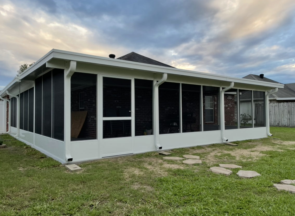 A house with a screened in porch in the backyard.