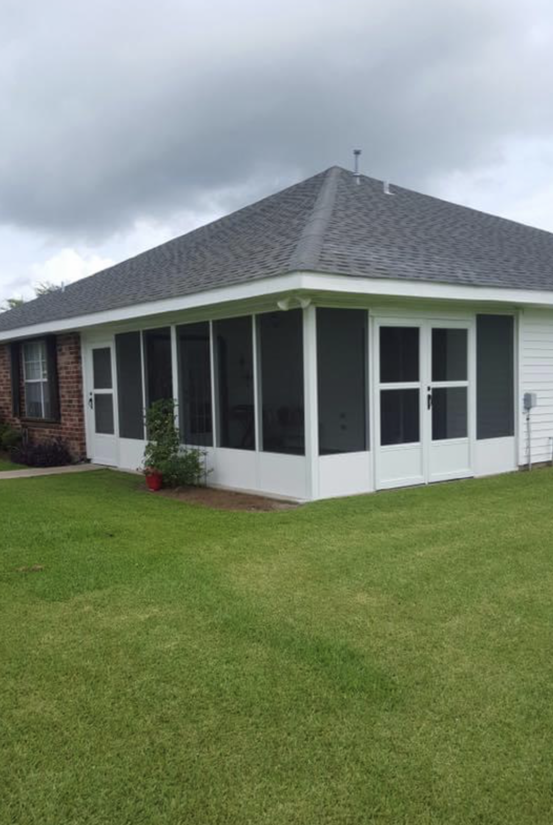 There is a screened in porch in the backyard of a house.